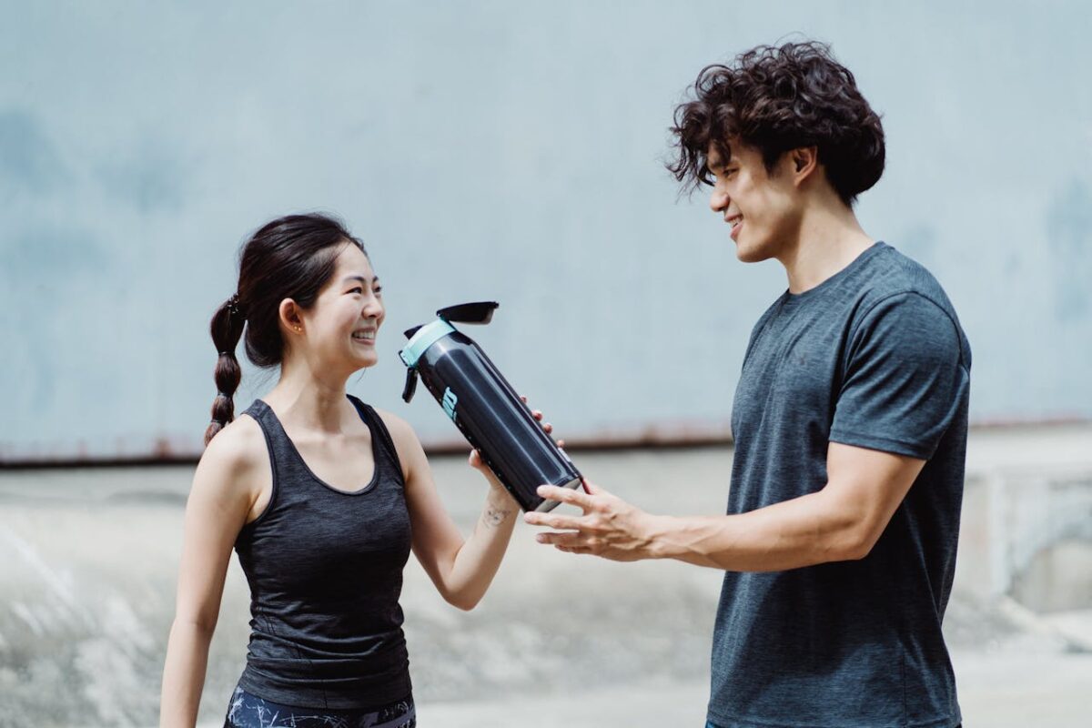 Smiling couple staying hydrated during outdoor summer workout.