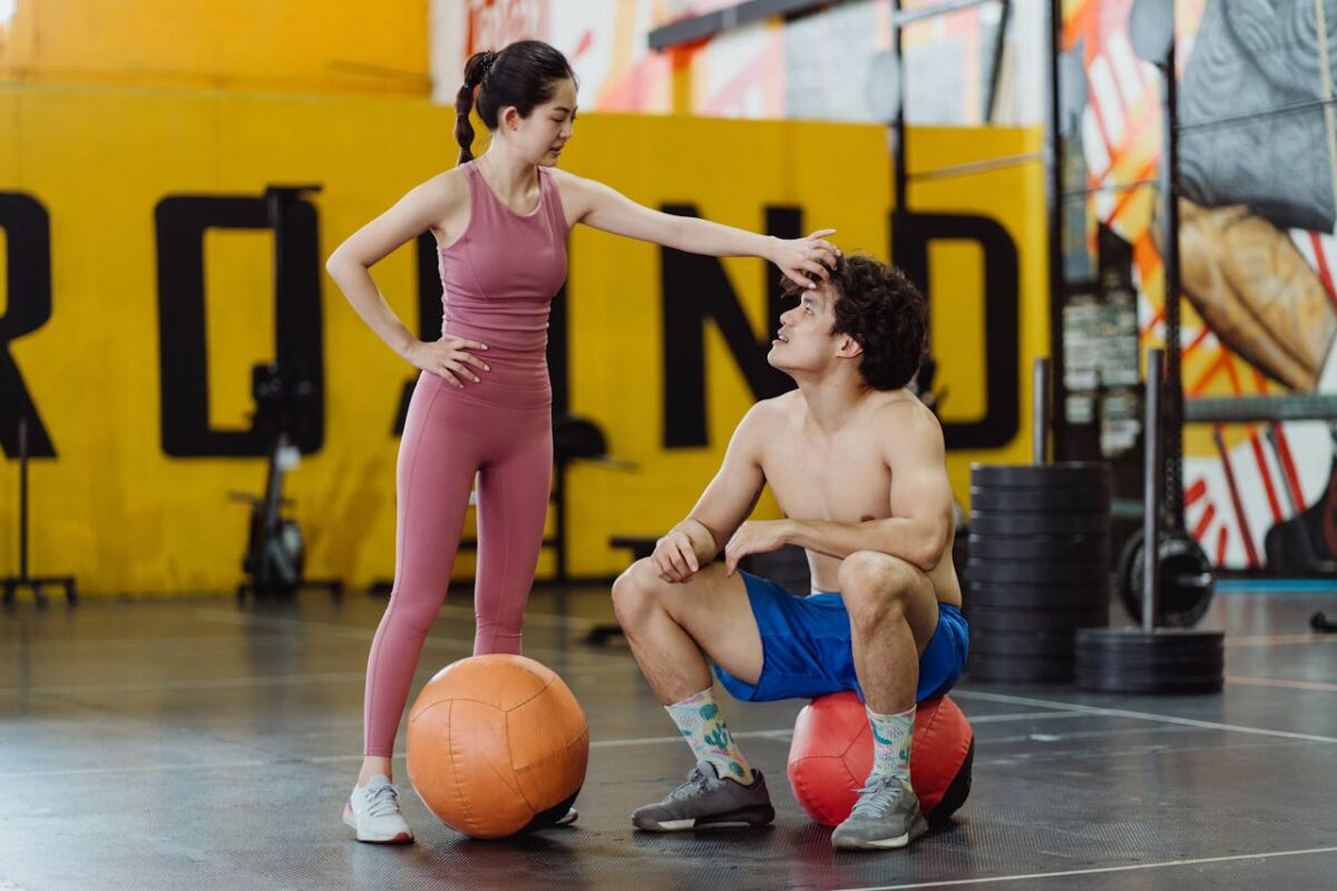 A couple sharing a moment in a gym setting with medicine balls, expressing fitness and togetherness.